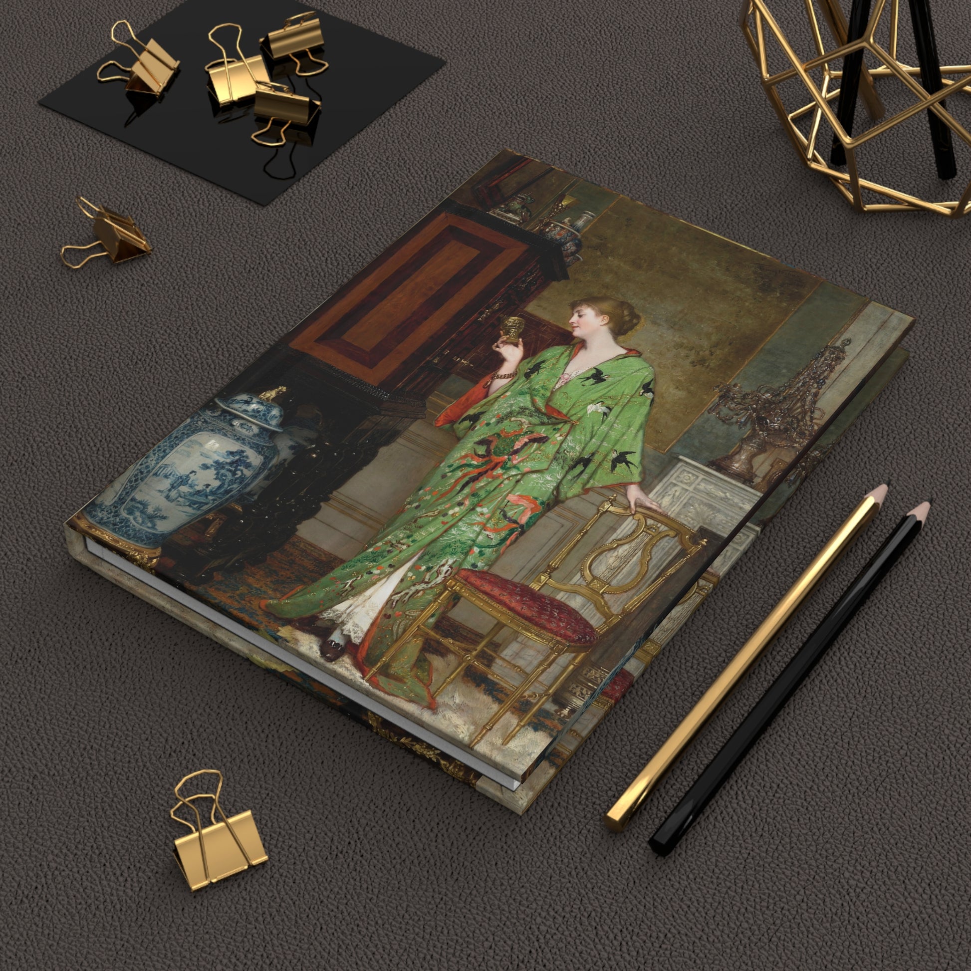 Notebook with artistic cover design on a dark surface with stationery items.