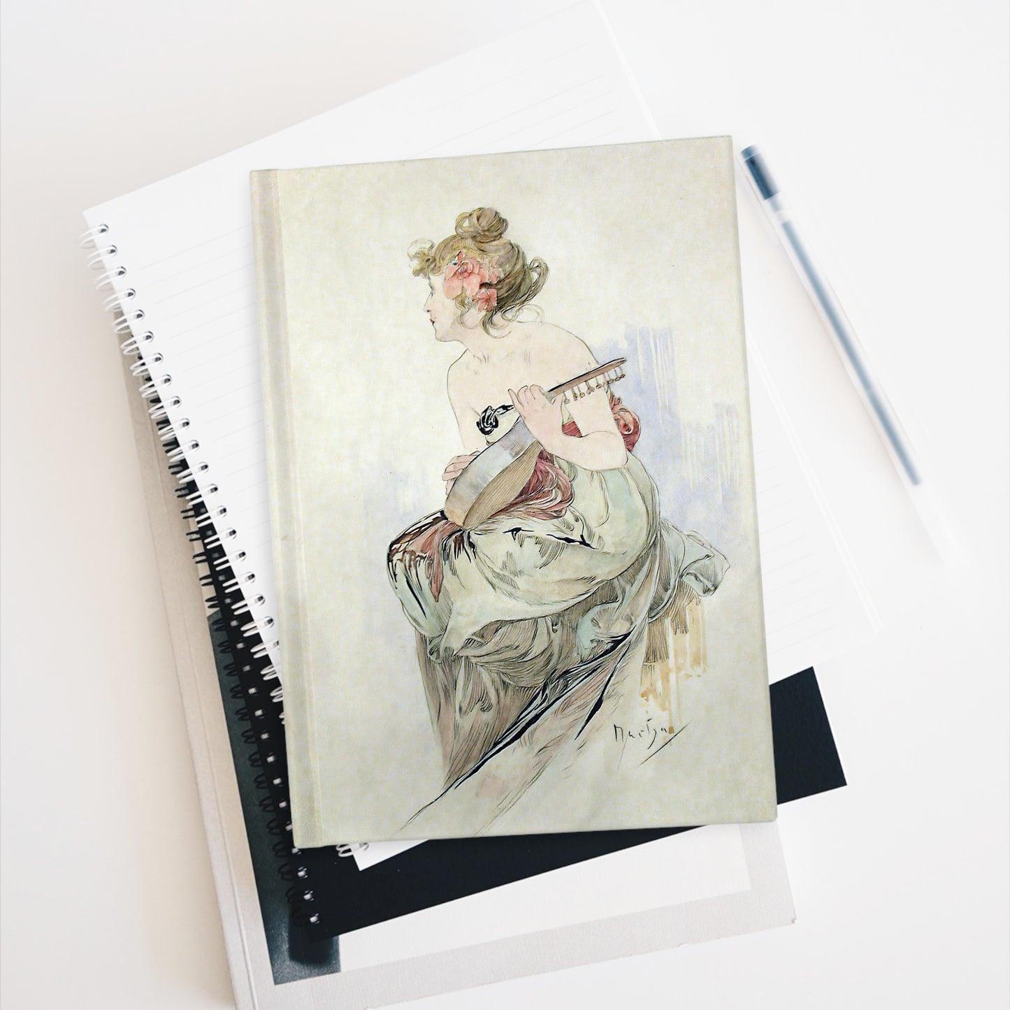 Notebook with artistic cover of a woman playing a guitar on a white surface.