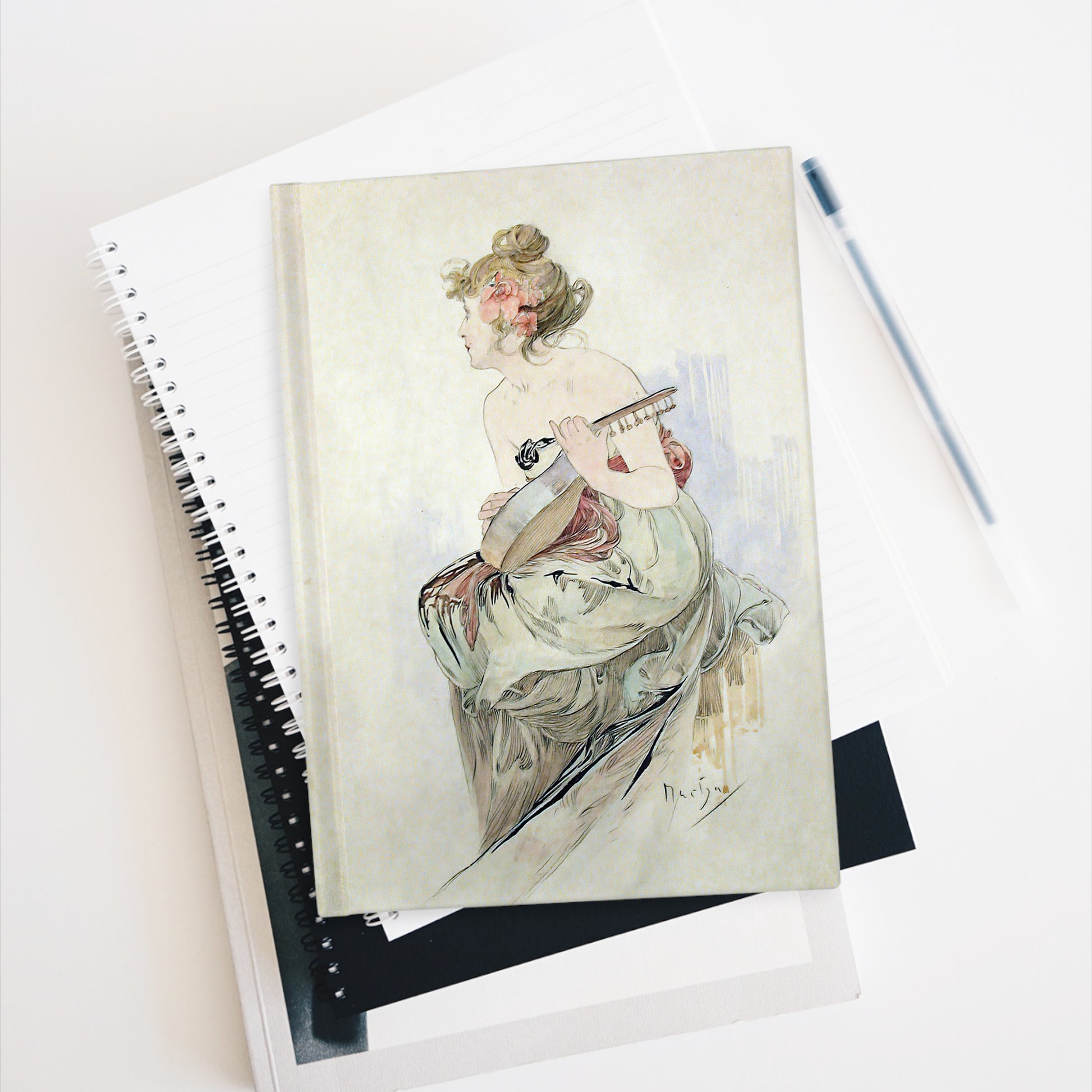 Notebook with artistic cover of a woman playing a guitar on a white surface.