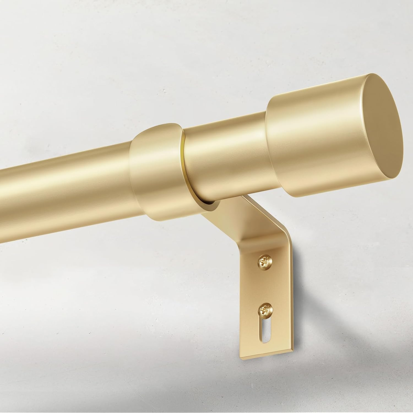 Gold curtain rod with bracket on a light gray background