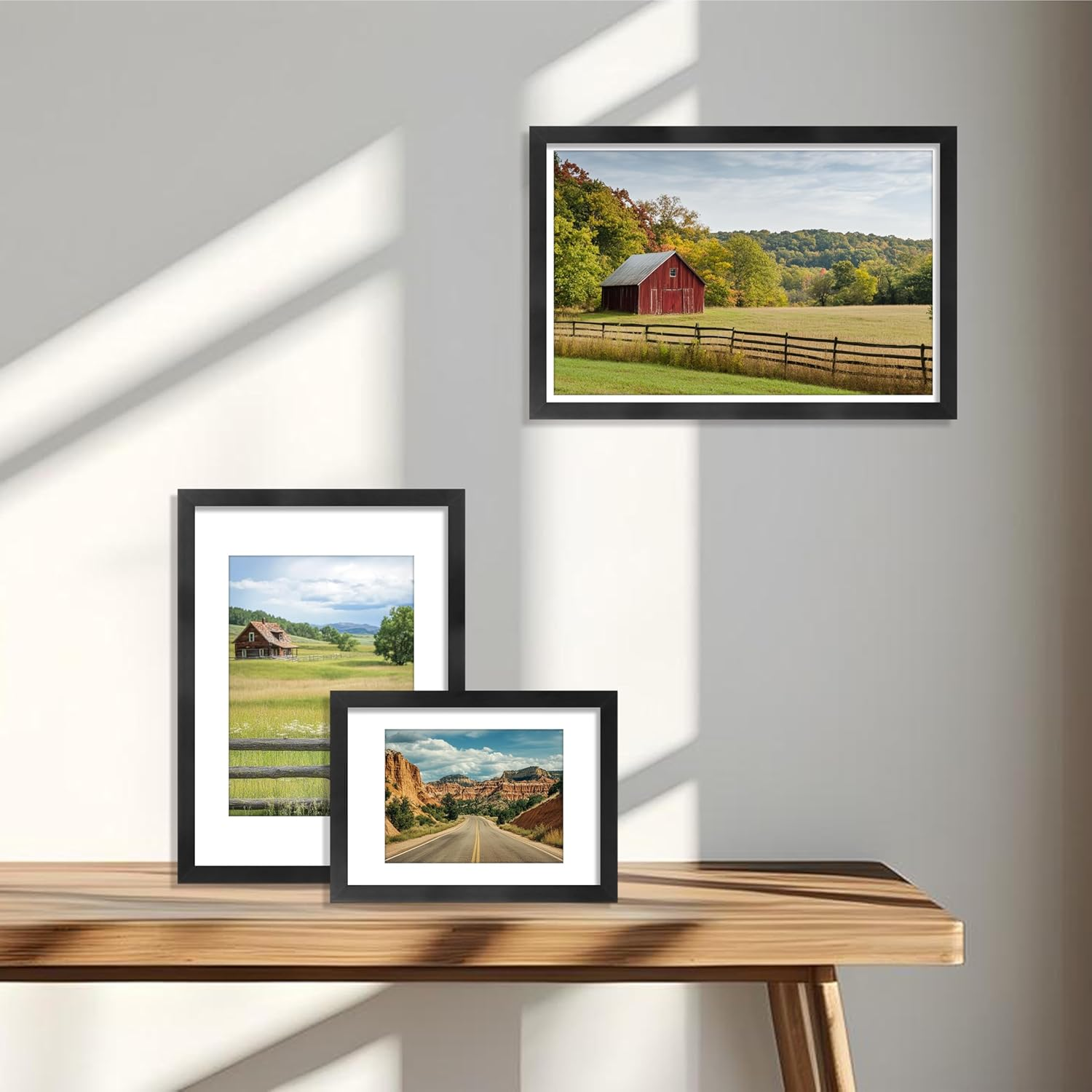 Framed landscapes on a wooden shelf with a white wall background