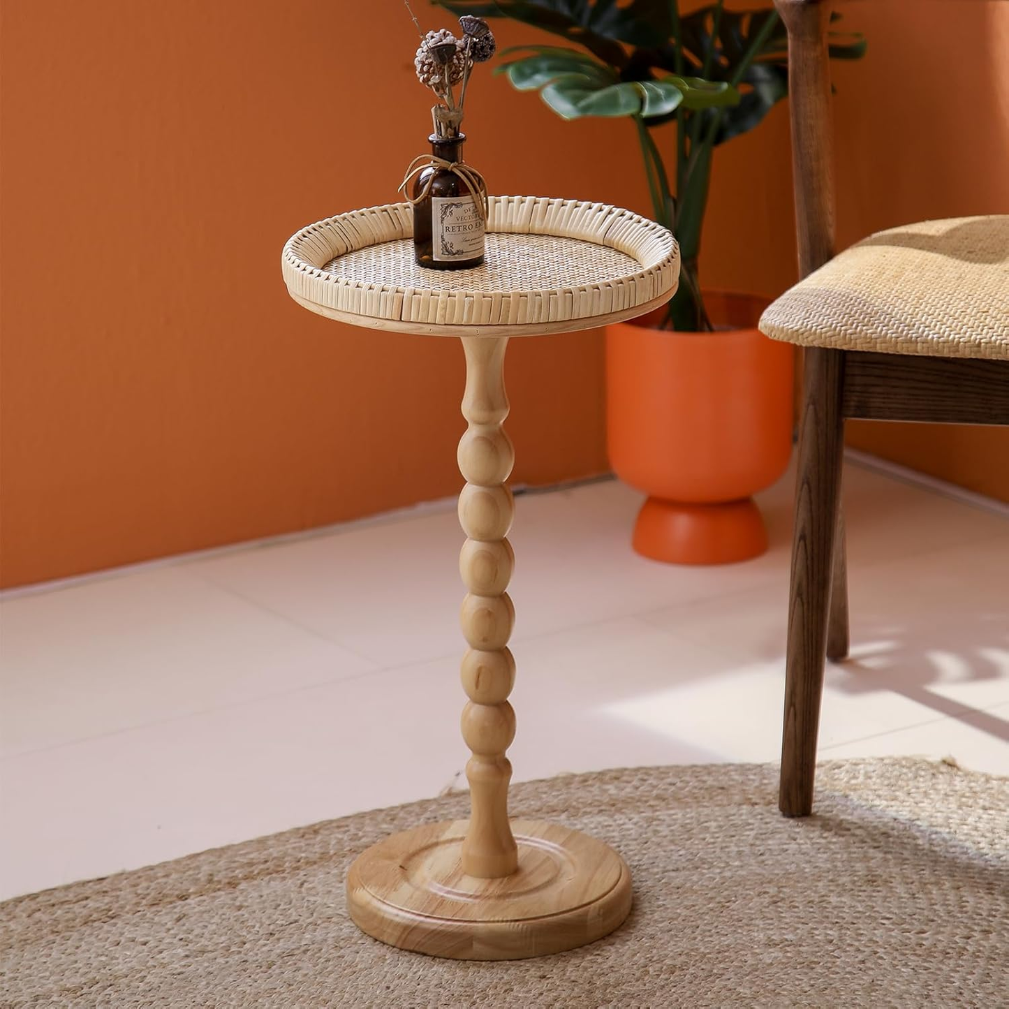 Wooden side table with wicker top in a room with an orange wall and plant.