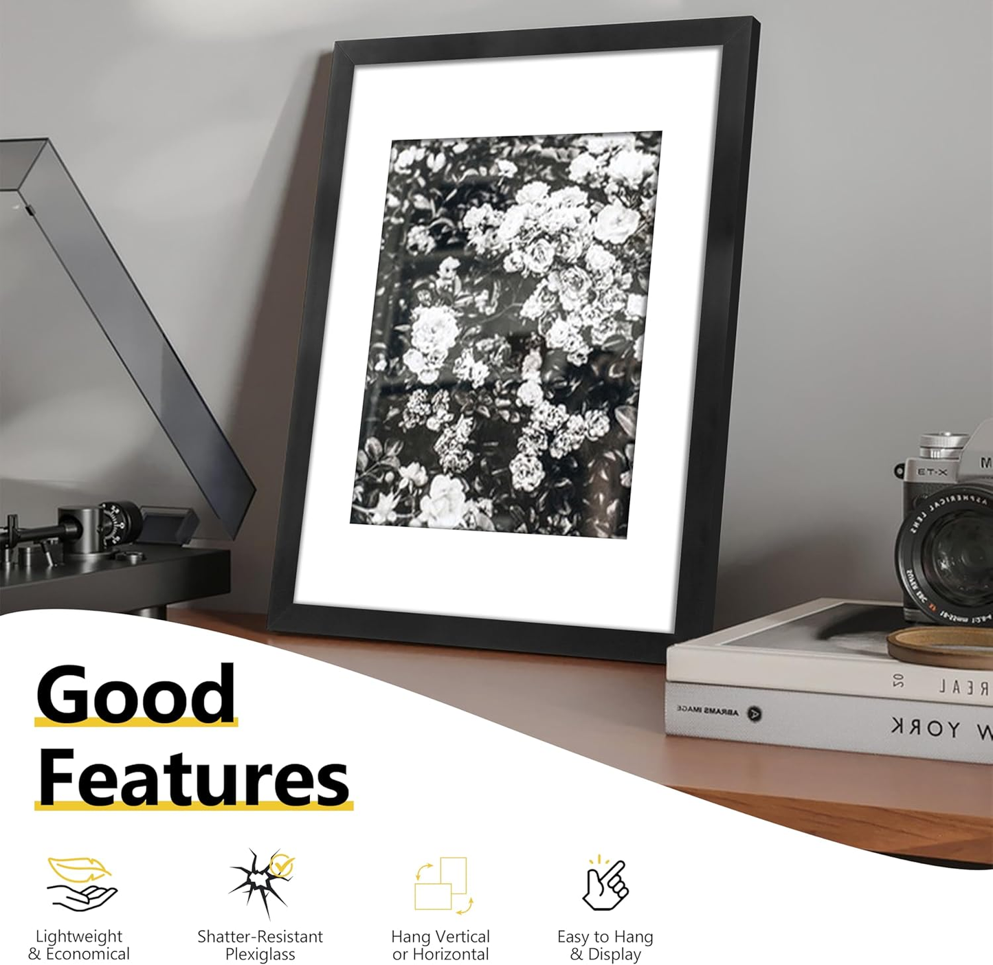 Framed black and white floral print on a shelf with books and a record player.